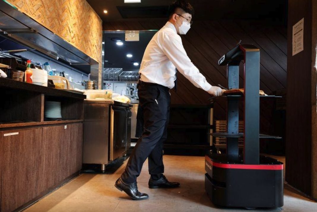 موظف يضع طعاما على روبوت يعمل بالذكاء الاصطناعي لخدمة الزبائن في مطعم في كوريا الجنوبية . رويترز